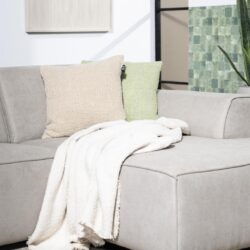Zachte neutrale banken met kleurrijke kussen en warme plaid in modern woonkamer.