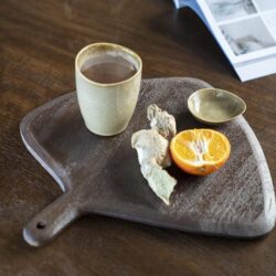Krijtbord snijplank met kop thee, sinaasappel en gember, houten tafel en open magazine voor een gezellige en natuurlijke uitstralingoor decoratie en meubel inspiratie.