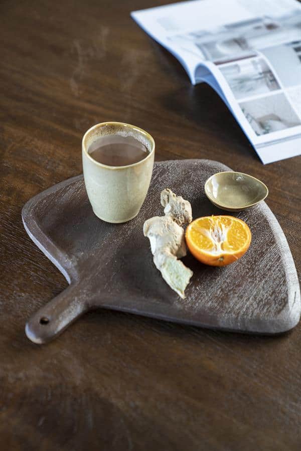 Krijtbord snijplank met kop thee, sinaasappel en gember, houten tafel en open magazine voor een gezellige en natuurlijke uitstralingoor decoratie en meubel inspiratie.
