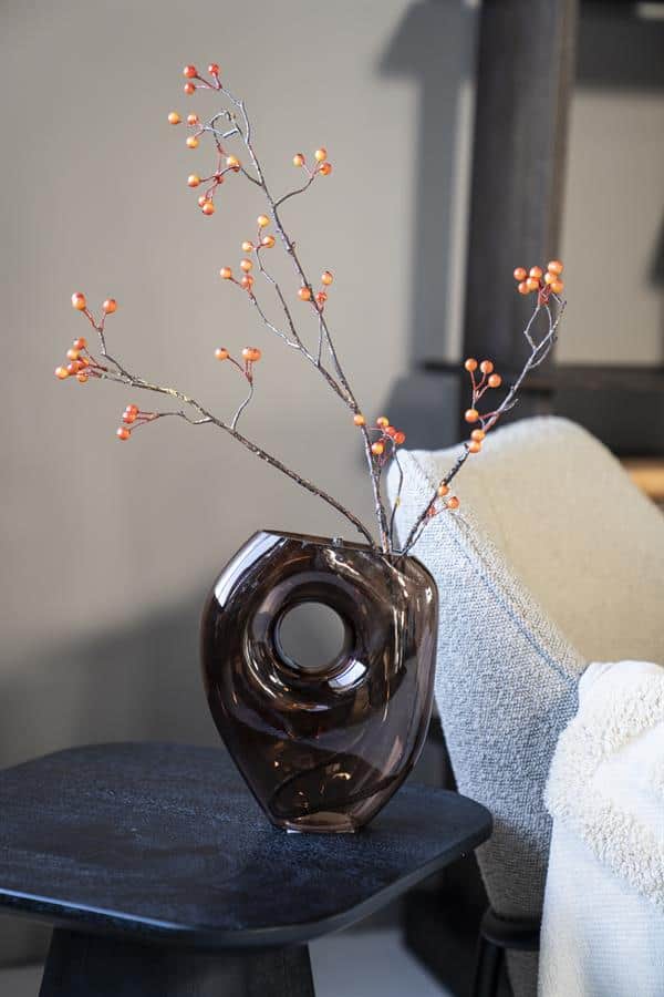 Elegant sieraden vaas met takje met oranjerode bessen, perfect voor moderne interieurversiering.