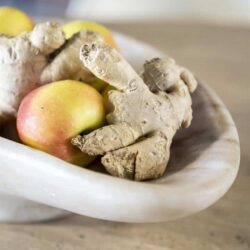Gember en appel in een witte kom op een houten tafel, seizoen- en keukeninspiratie, natuurlijke gezonde ingrediënten, verse kruiden en fruit, topkwaliteit voedsel.