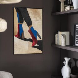 Kleurrijke wandkunst met voeten in opvallende sokken, moderne sfeer in interieur met donkere muren en zwarte planken.