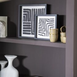 Modern wanddecoratie met abstracte zwart-wit kunstwerken op een donkergrijze wand, gecombineerd met keramische en houten decoratieobjecten, perfect voor een eigentijdse interieurstijl.