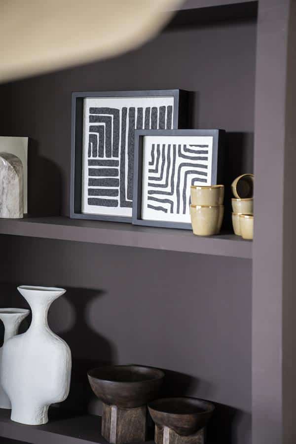 Modern wanddecoratie met abstracte zwart-wit kunstwerken op een donkergrijze wand, gecombineerd met keramische en houten decoratieobjecten, perfect voor een eigentijdse interieurstijl.