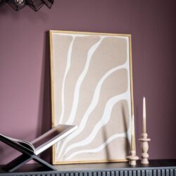 Eettafel met zwart frame en open boek, decoratief canvas met beige en witte abstracte organische lijnen en twee stijlvolle witte kandelaars op een donkergrijze meubel tegen een paarse muur.