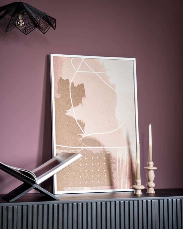 Moderner abstract kunstprint met zachte pastelkleuren en witte lijnen, geschikt voor woondecoratie, vlakbij kaarsen en een boek op een donkergrijze meubel tegen een paarse muur.