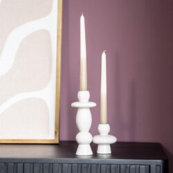 Elegante witte kandelaars op een zwart meubelstuk, perfect voor stijlvolle interieurdecoratie en het creëren van een gezellige sfeer in huis.