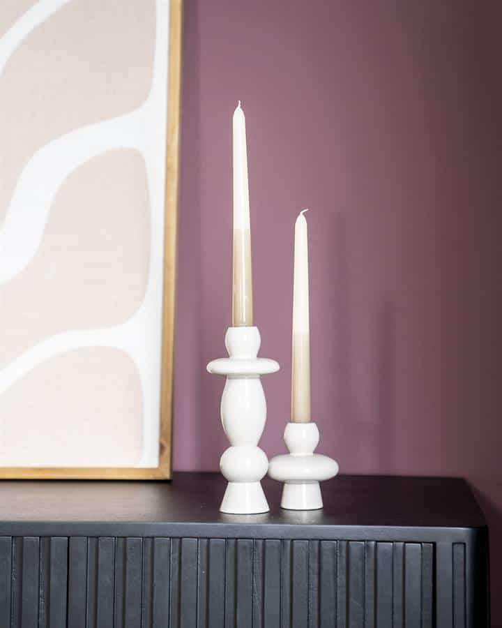 Elegante witte kandelaars op een zwart meubelstuk, perfect voor stijlvolle interieurdecoratie en het creëren van een gezellige sfeer in huis.