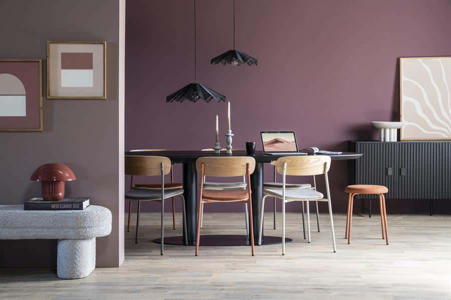 Elegante eettafel met houten stoelen en moderne lampen in een stijlvol interieur met muurdecoraties.