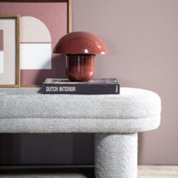 Moderne sculpturale kruk tafel in gerecycled beton met abstract kunst op de achtergrond.