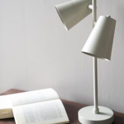 Moderne witte leeslamp op nachtkastje met open boek voor gezellige leeshoek interieur design.