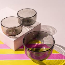 Vazen van gekleurd glas op een kleurrijke tafel met kleurrijke patronen, perfect voor modern interieur en meubelaccessoires.
