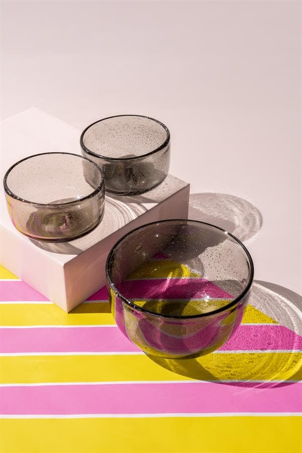 Vazen van gekleurd glas op een kleurrijke tafel met kleurrijke patronen, perfect voor modern interieur en meubelaccessoires.