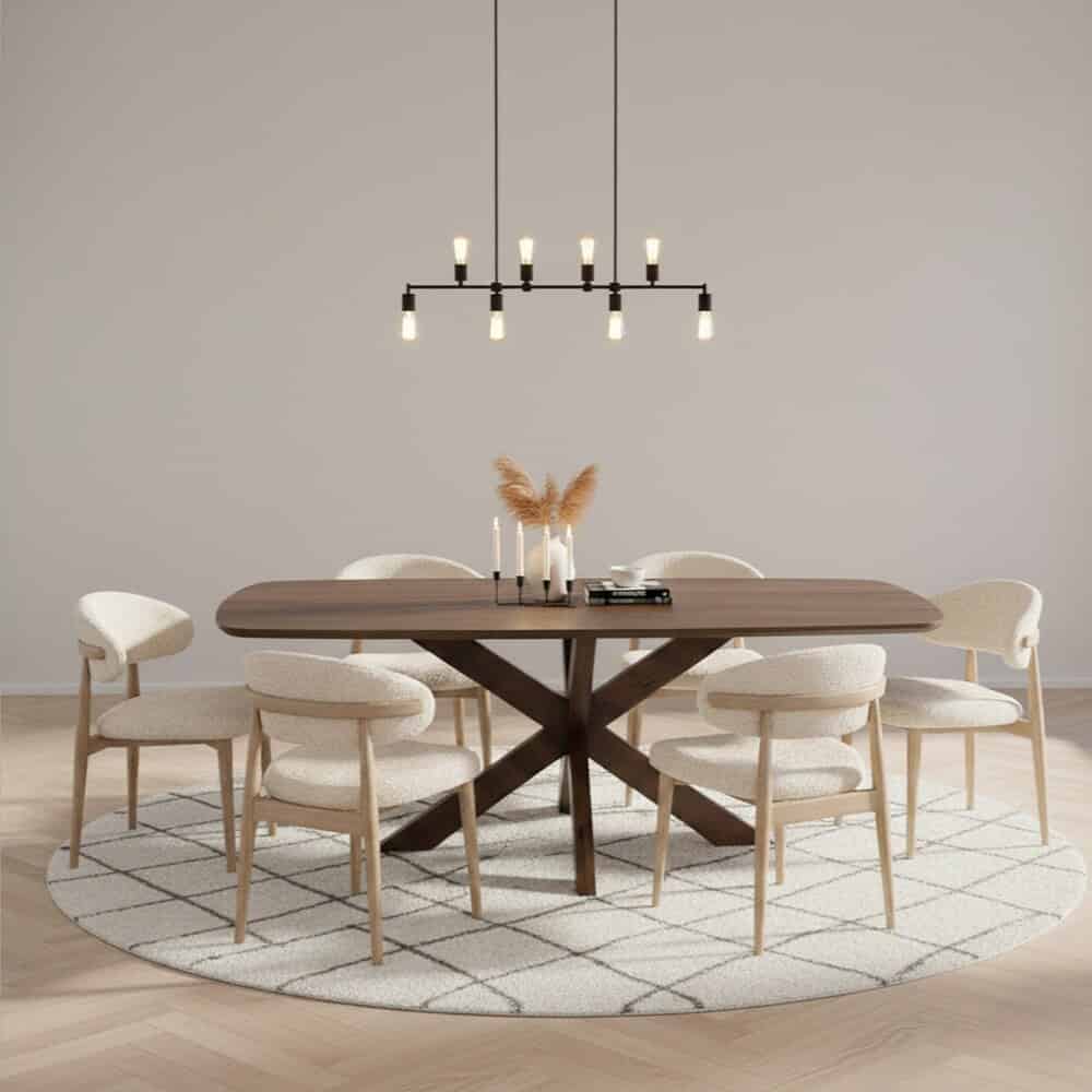 Eettafel met houten frame en acht comfortabele upholstered stoelen, moderne hanglamp en decoratieve vazen met takken op een ronde tapijt, strakke en sfeervolle interieurstijl. Mangohouten meubels