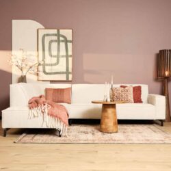 Modern witte bank in een gezellige woonkamer met roze en beige decoratie, houtenvloer en stijlvolle accessoires, perfect voor een warm en eigentijds interieur.