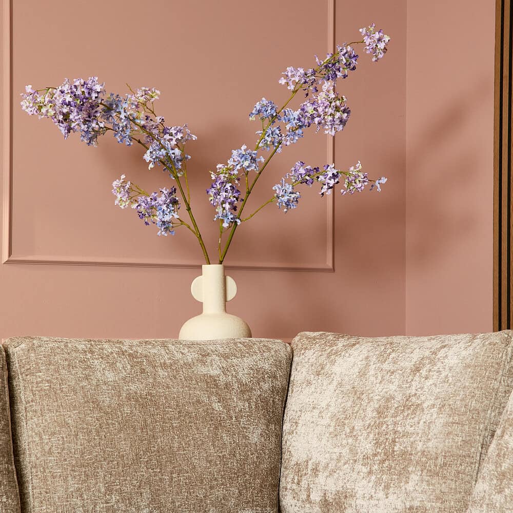 Deense fluwelen bank en een luxe vaas met een boeket blauwe bloemen op een roze wandachtergrond, vintage interieurstijl, elegant en warm woondecor.