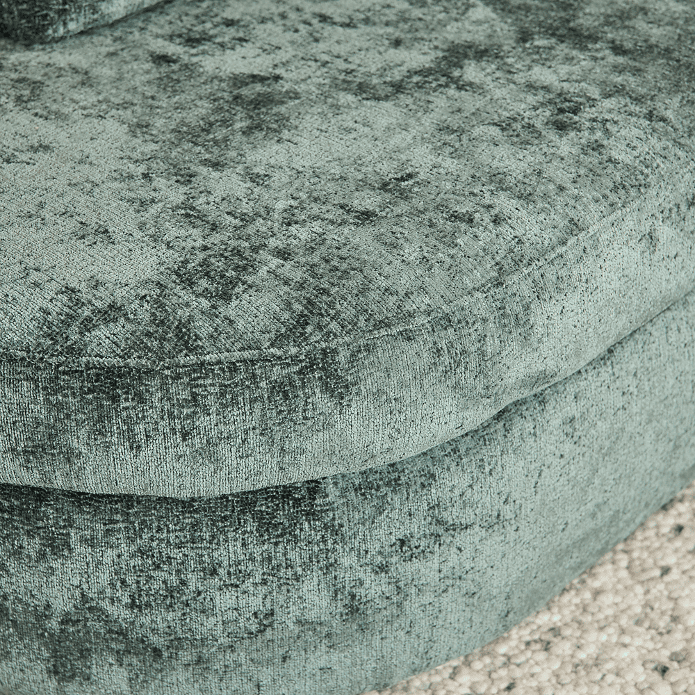 Zachte fluwelen bekleding van een fauteuil met een rijke, groene tint en een luxe uitstraling, perfect voor een elegante en comfortabele woonkamer inrichting.