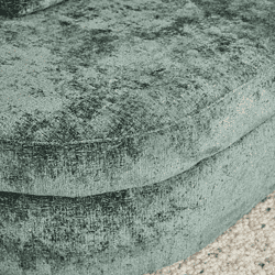 Zachte fluwelen bekleding van een fauteuil met een rijke, groene tint en een luxe uitstraling, perfect voor een elegante en comfortabele woonkamer inrichting.