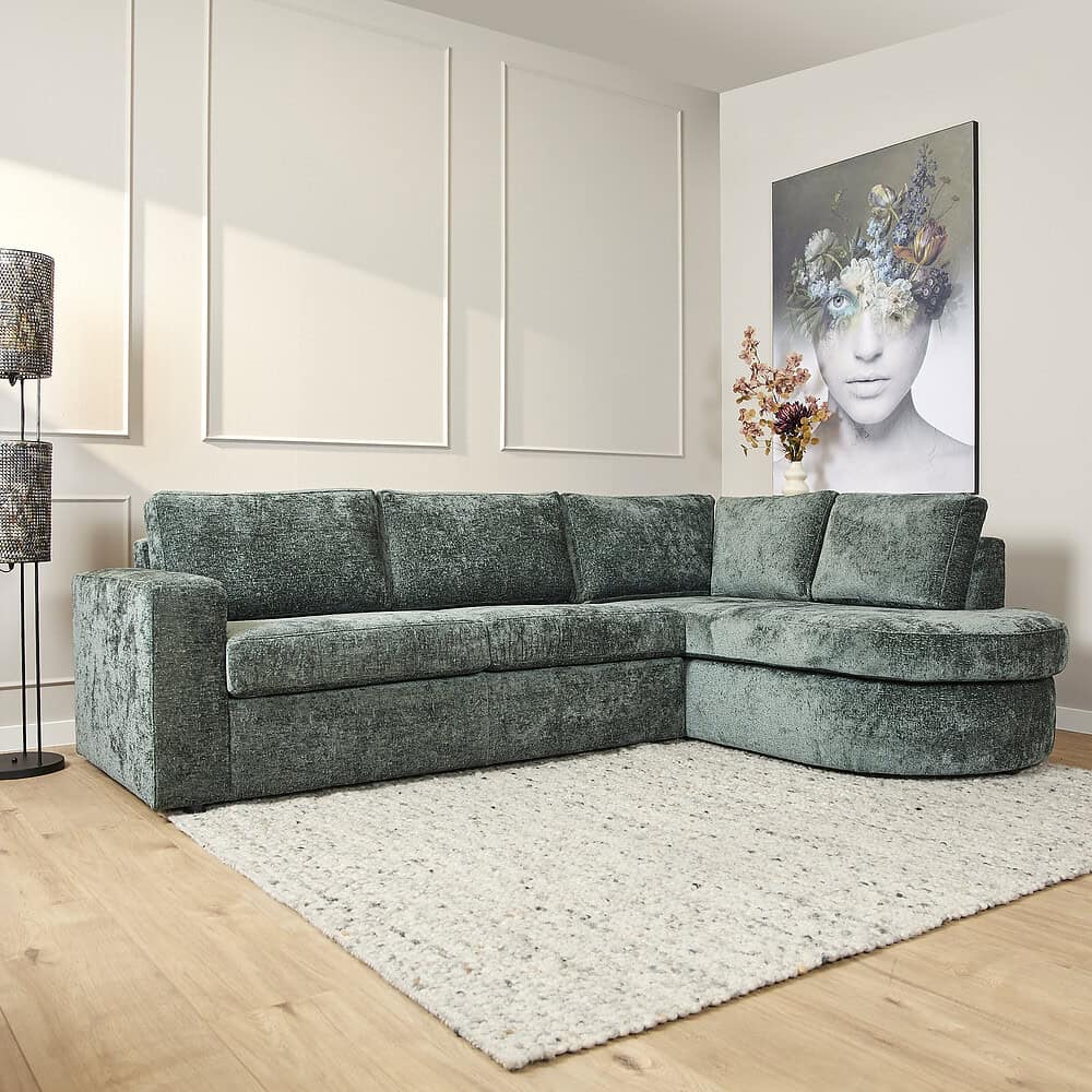 Luxe groene velvet hoekbank in modern interieur met witte wandpanelen en abstract kunstwerk, perfect voor stijlvolle zithoeken en comfort.