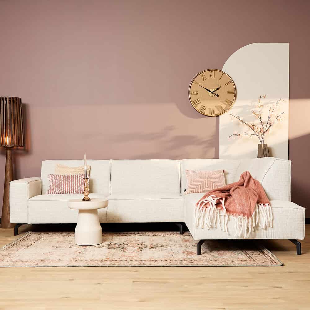 Modern wit woonkamerbank met pastel accessoires en tapijt, natuurlijke houten vloer, stijlvolle wandklok en decoratieve lamp, creëren een Scandinavische sfeer met Mokana Meubelen.