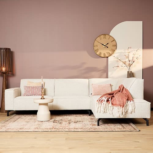 Modern wit woonkamerbank met pastel accessoires en tapijt, natuurlijke houten vloer, stijlvolle wandklok en decoratieve lamp, creëren een Scandinavische sfeer met Mokana Meubelen.
