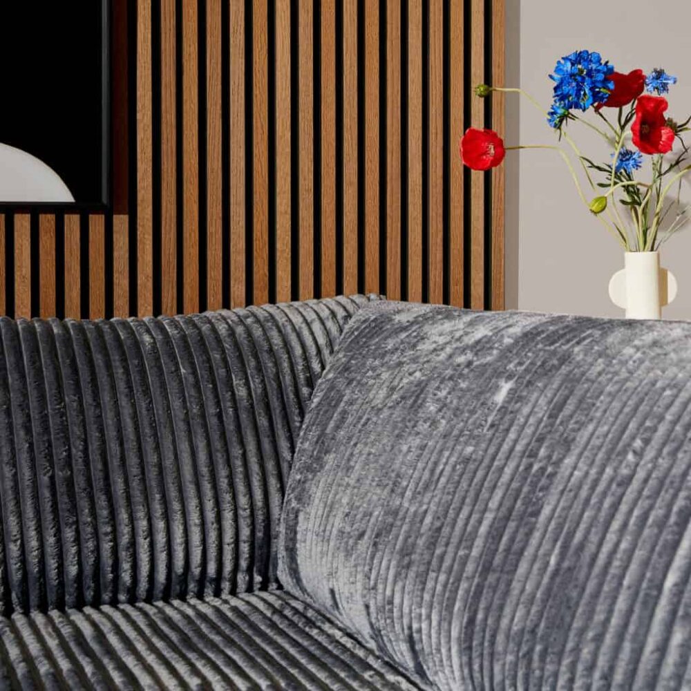 Hoge resolutie foto van een modern, velvet gestoffeerd bankje en een sierlijke vaas met kleurrijke bloemen op een houten wand, perfect voor het promoten van stijlvolle meubels en interieuradvies van Mokana Meubelen.