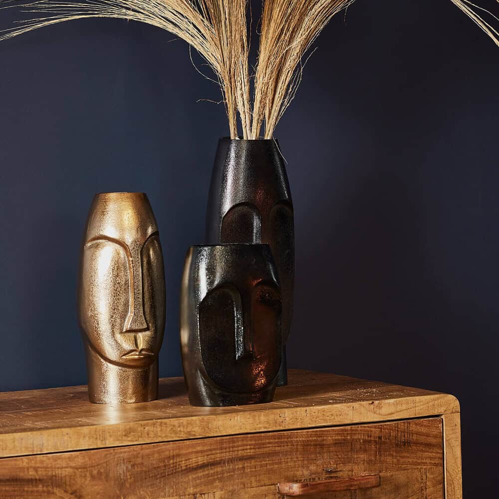Unieke vazen met Afrikaanse maskers decoratief op een houten meubelstuk, geschikt voor stijlvolle interieurdecoratie en wandversiering met natuurlijke materialen.