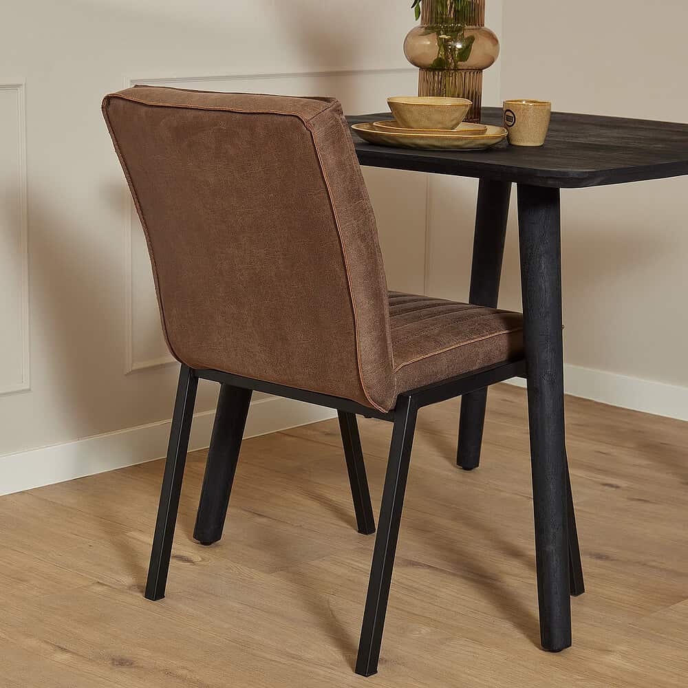Robuuste eetkamerstoel met cupru leren bekleding en zwart houten frame, perfect voor een industrieel of modern interieur.