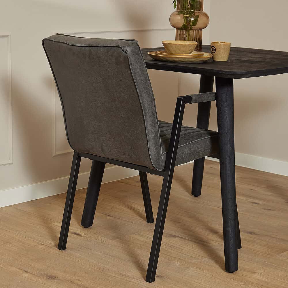 Elegante eetkamerstoel met bekleding in donkergrijze stof en zwart metalen frame, stijlvolle houten tafel met decoratieve vazen en servies voor een moderne woonstijl.