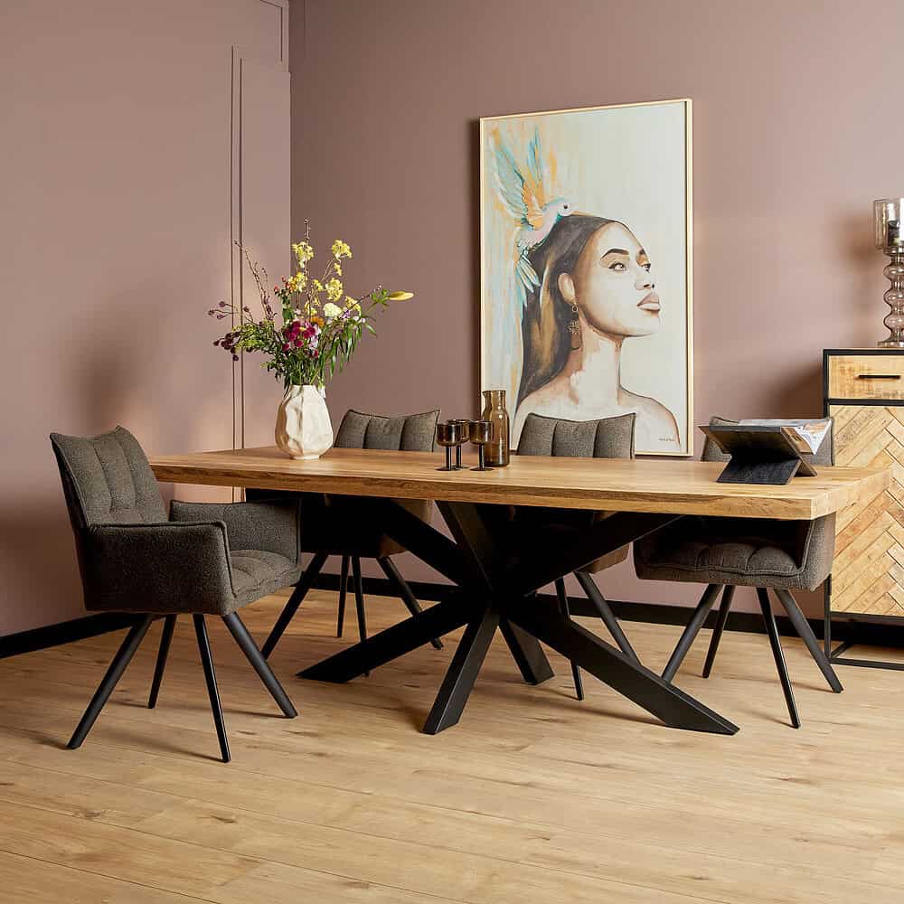 Großer Esstisch aus Holz mit schwarzem Metallgestell, umgeben von vier Teppichstühlen in einem modernen Interieur, dekorative Vase mit Blumen und ein buntes Kunstwerk an der Wand.