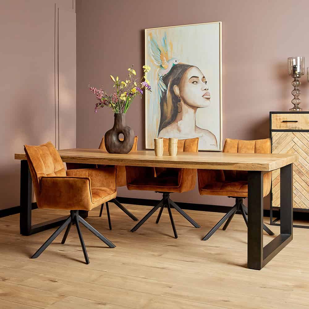 Antiek houten eetkamertafel met zwart metalen onderstel en zes bijpassende oranje velvet eetkamerstoelen, modern interieur met kunstwerk en decoratieve accessoires.