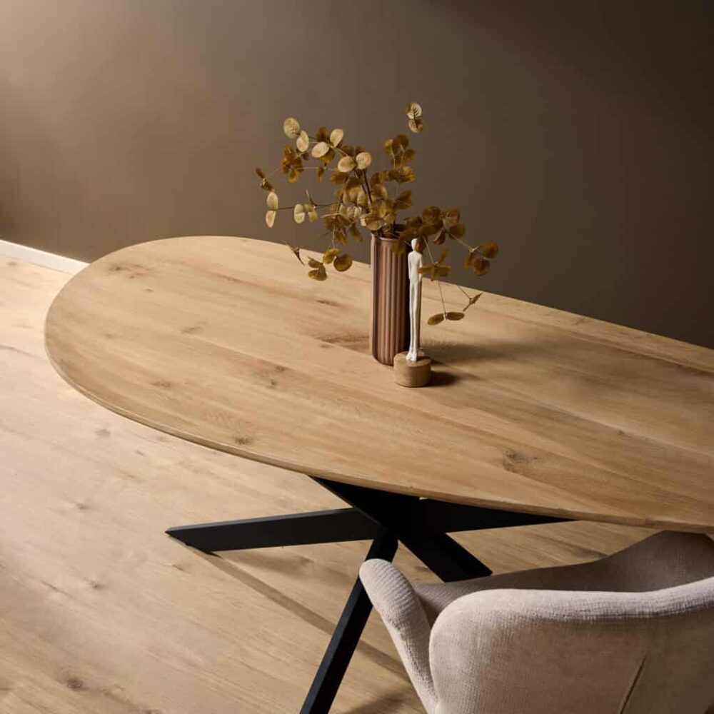 Minimalistisch eettafel van massief hout met een zwart metalen onderstel, gecombineerd met een moderne vaas en decoratieve accessoires voor een stijlvol interieur.