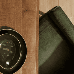 Kunststoffen servies op houten tafel naast groene lederen fauteuil.