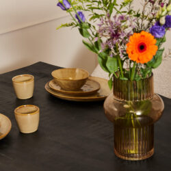 Vaas met zomerbloemen op een donker houten eettafel in een modern interieur.