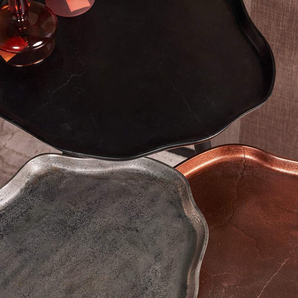 Grote zwart marmeren bijzettafel met afgeronde randen, stijlvolle eetkast, en rustieke koperen schaal, perfect voor moderne en industriële interieurdecoratie.