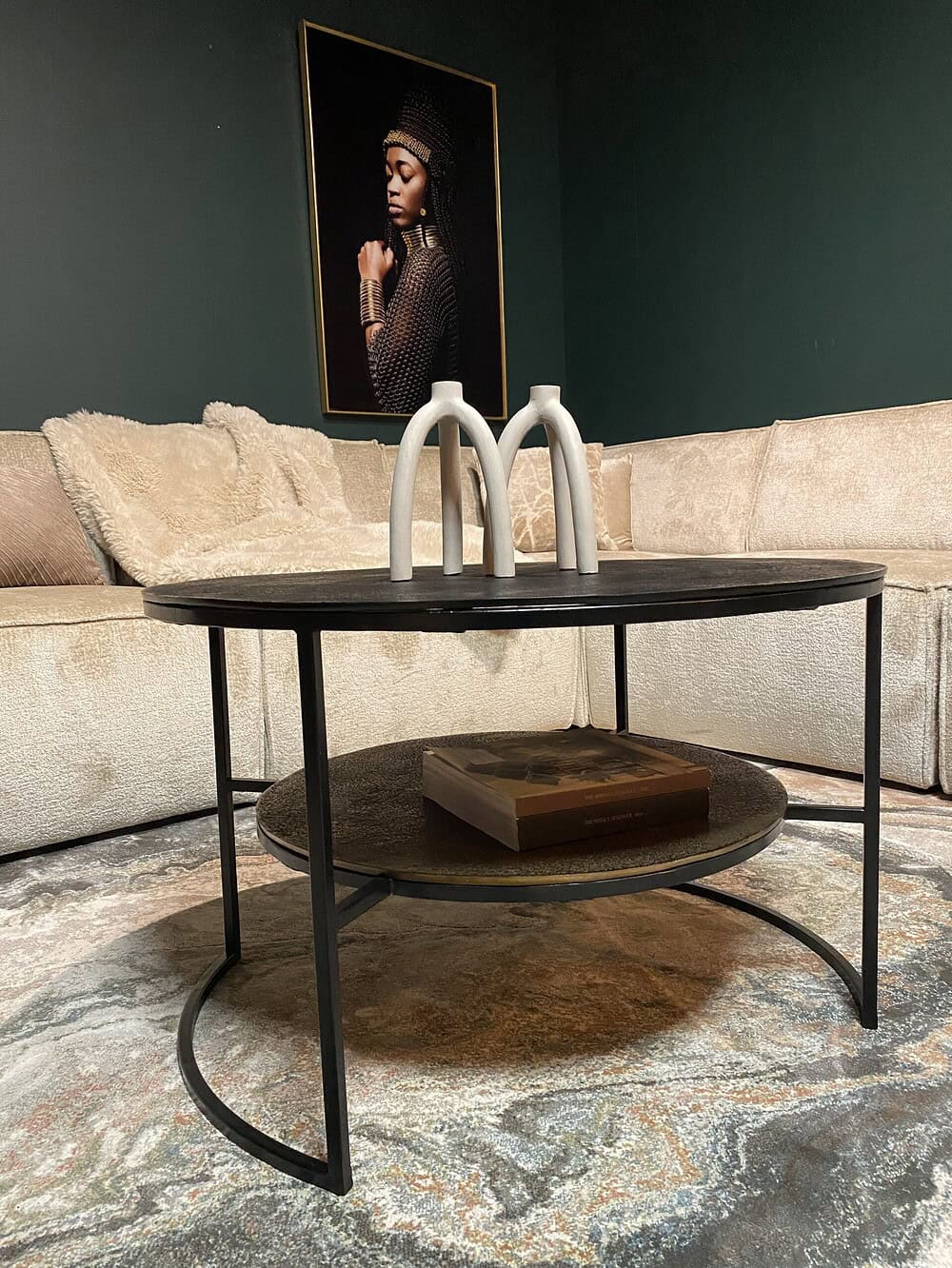 Elegante salontafel met zwart houten blad en metalen frame, inclusief twee lagen voor extra opbergruimte, in een modern interieur met kunst en comfortabele sofa.
