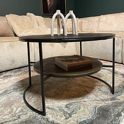 Elegante salontafel met zwart houten blad en metalen frame, inclusief twee lagen voor extra opbergruimte, in een modern interieur met kunst en comfortabele sofa.