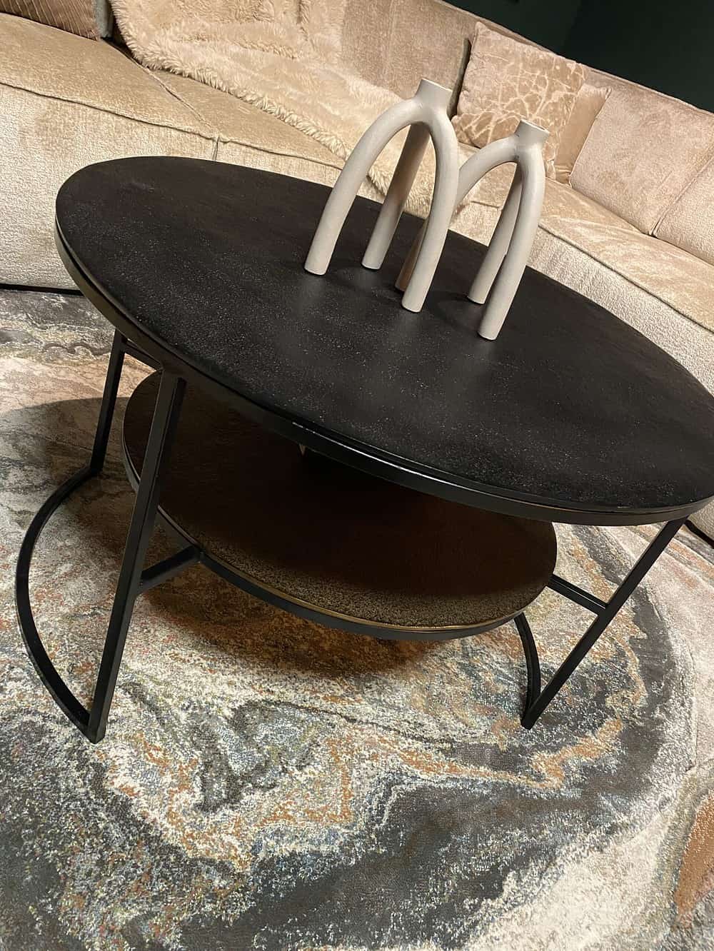 Elegante zwarte eettafel met een bijpassende onderconstructie en sierlijke decoratieve accessoires voor een stijlvol interieur.