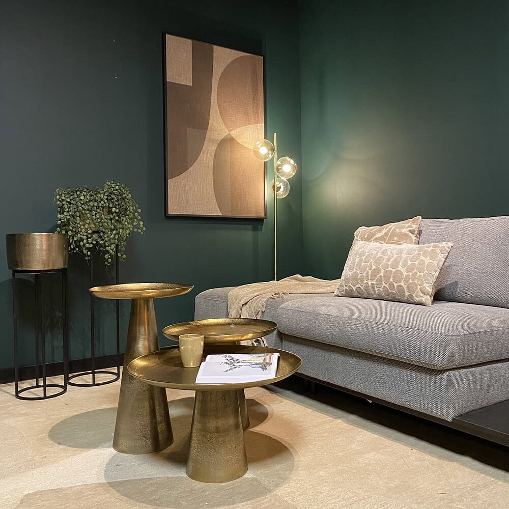 Elegante woonkamer inrichting met luxe metalen bijzettafels, modern vloerlamp en een comfortabele bank, gecombineerd met decoratieve kussens en kunst aan de muur, perfect voor stijlvolle interieurs.