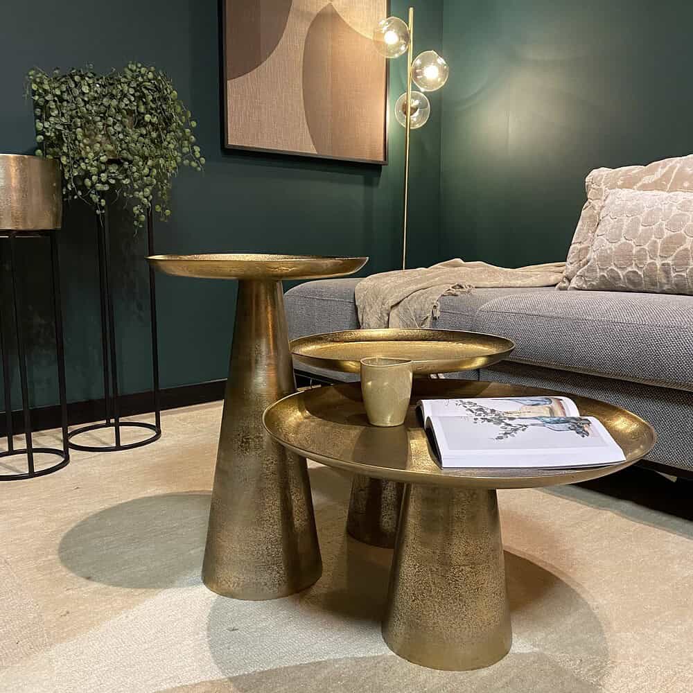 Elegante gouden bijzettafels in een modern interieur met comfortabele bank, planten en kunstwerken, perfect voor elegante woonkamer decoratie en stijlvolle meubelkeuzes.