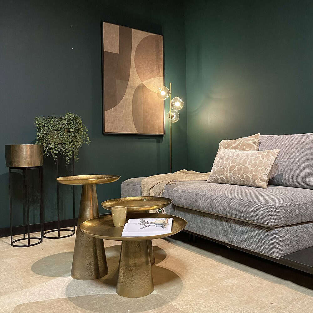 Modern woonkamer met comfortabele stoffen bank, goudkleurige bijzettafels en decoratieve muurkunst, stijlvolle interieur styling door Mokana Meubelen voor een luxe woonervaring.