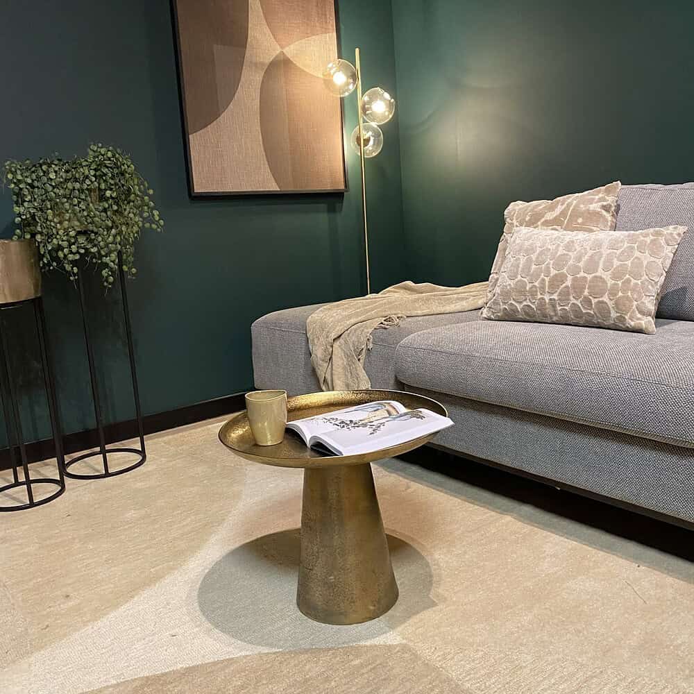 Elegante woonkamer met vintage gouden salontafel, downlights, groen wanddecor en comfortabele grijze bank met decoratieve kussens, perfect voor modern wonen.