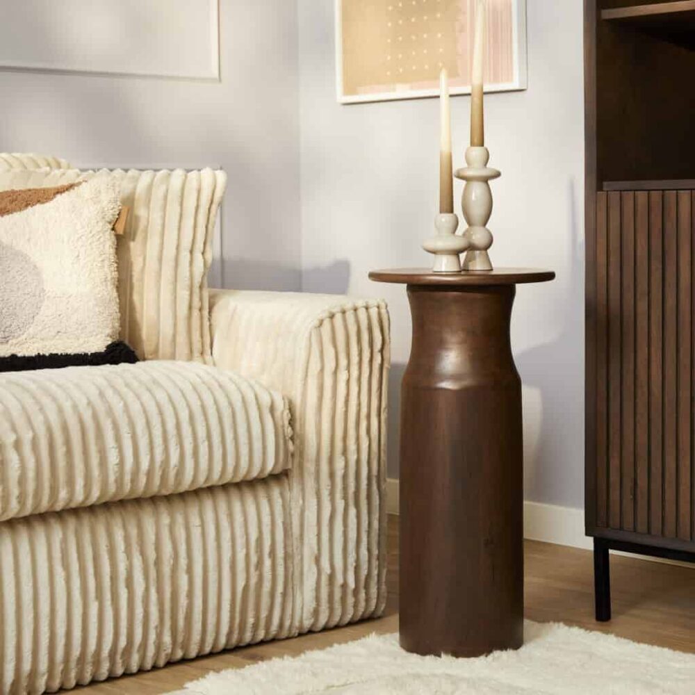 Grote houten bijzettafel in een modern woonkamer met decoratieve kandelaars en textuurarm banken. Mokana Meubelen specialiseert zich in hoogwaardige, stijlvolle meubels op maat voor elke inrichting.