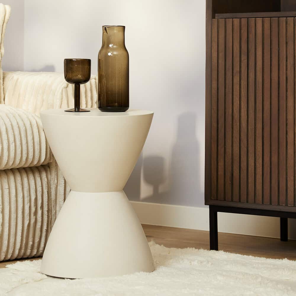 Stijlvolle witte bijzettafel met unieke vorm in een living, gecombineerd met decoratieve glasobjecten voor een modern interieur.