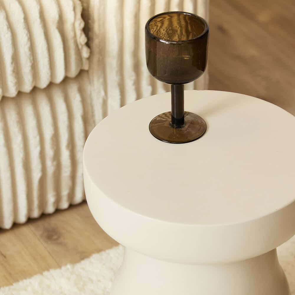 Robuuste zwarte glas wijnhouder op een wit bijzettafeltje in een modern interieur.