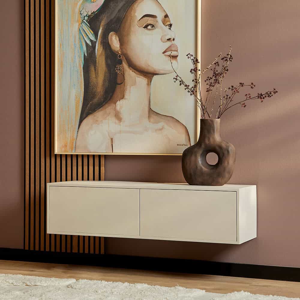 Strakke witte wandplank met gesloten schuifdeuren onder groot kunstwerk en beige vaas met takken, modern interieur, stijlvolle meubels, Mokana Meubelen, woonkamer decoratie, tijdloos design.