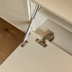 Deur scharnier en gas demper op wit kast meubel, meubel hardware details.