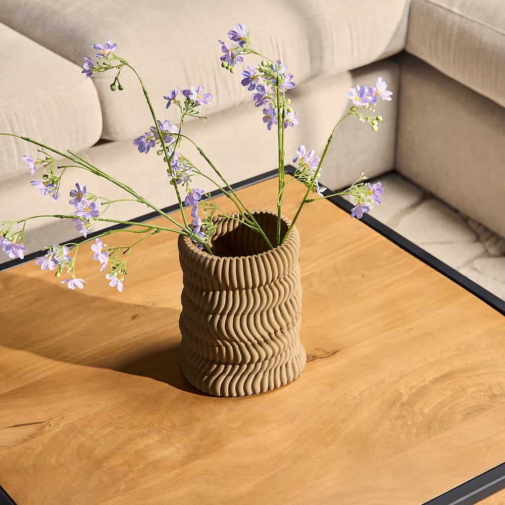 Gezicht op een decoratieve, textuurrijke keramieken vaas met bloemen op een houten salontafel in een moderne woonkamer. Perfecte meubelstijl inspiratie met natuurlijke materialen en stijlvolle accessoires.