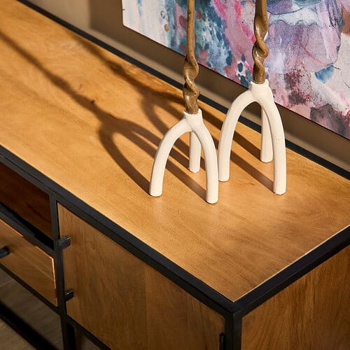 Elegante houten dressoir met zwart metalen frame, perfect voor moderne interieurs, gecombineerd met kleurrijke kunst en unieke decoratie zoals de sculptuur met gedraaide houten elementen.