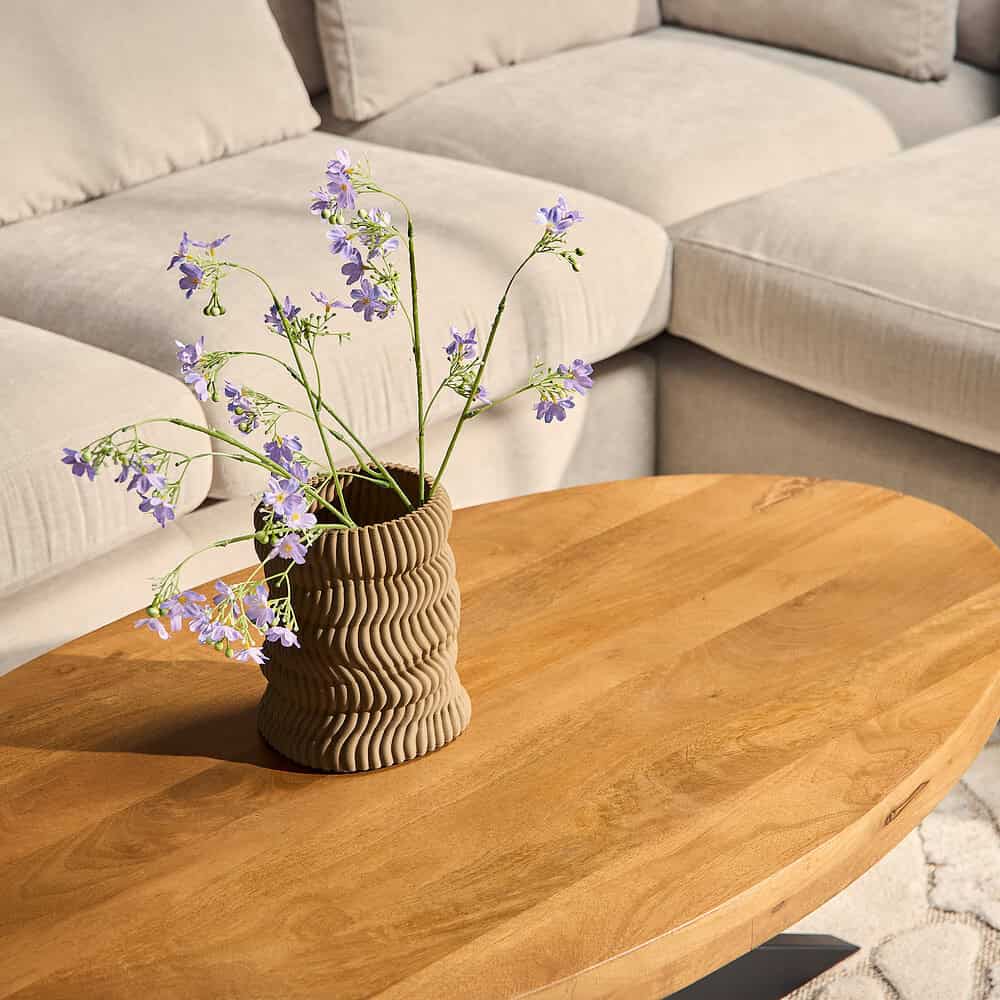 Elegante stoffen tafel met bijpassende bank en een decoratieve vaas met bloemen, perfect voor een modern woonkamer.